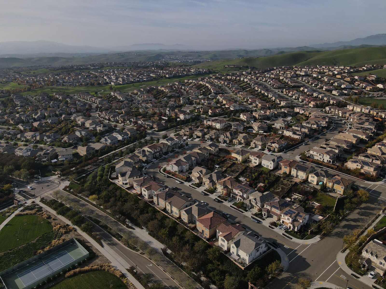 Wide aerial view of a master-planned residential tract of tile-roofed houses