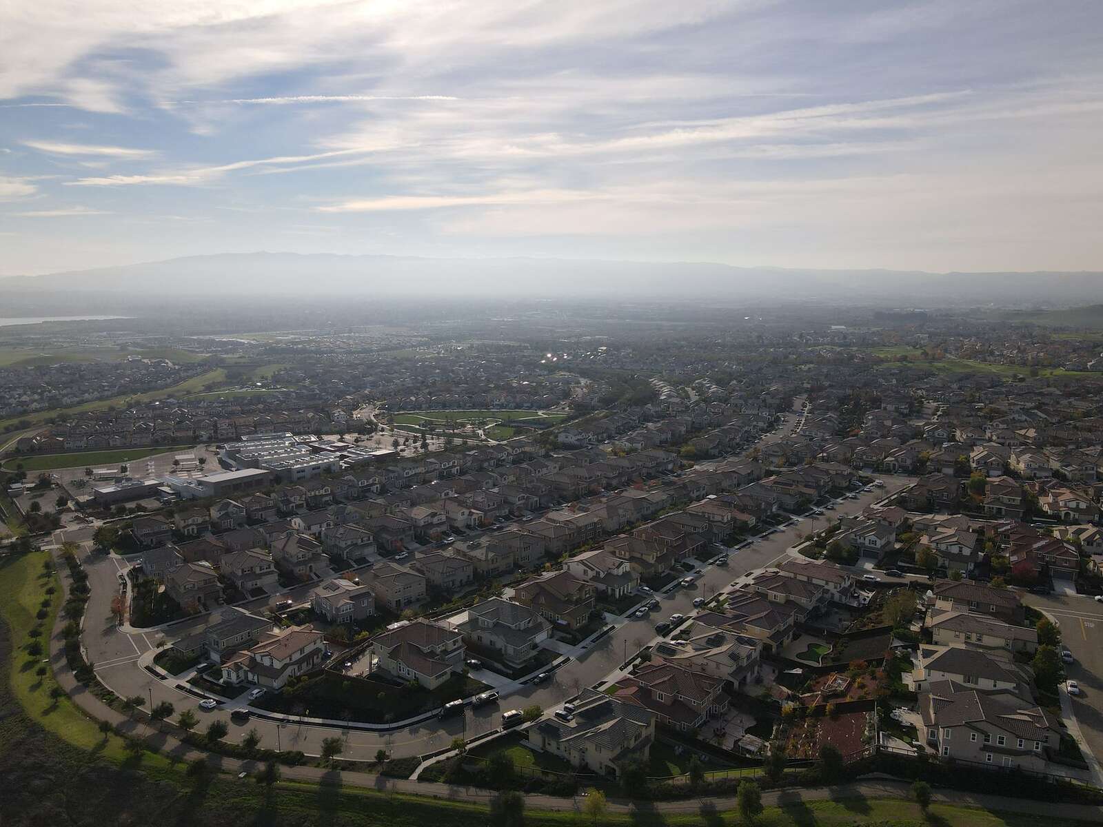 Aerial view of a suburban tract with open hills rising behind the last row of houses