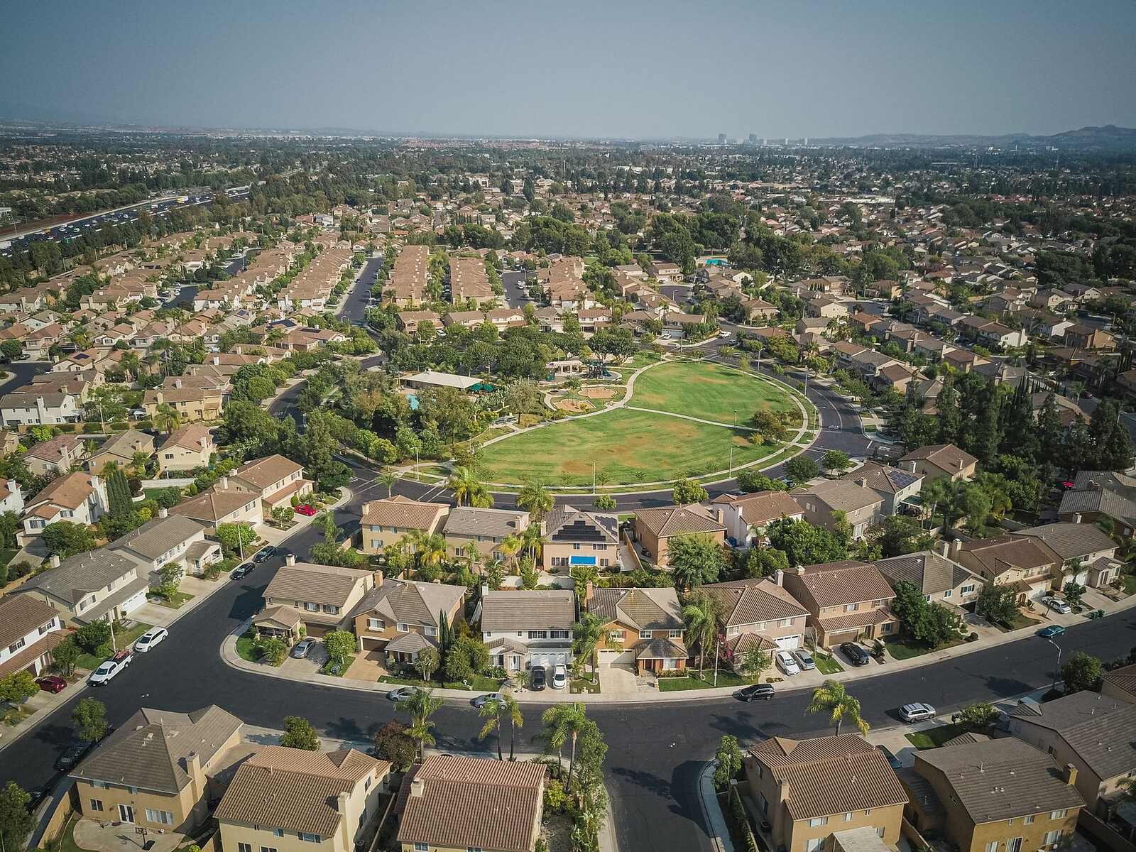 Aerial view of a suburban tract of tile-roofed houses around a central park