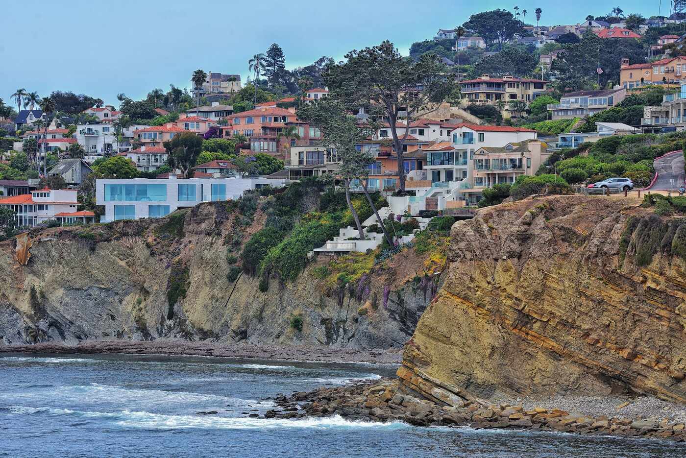 Houses stepped down a San Diego hillside above coastal cliffs, dense planting between every roof