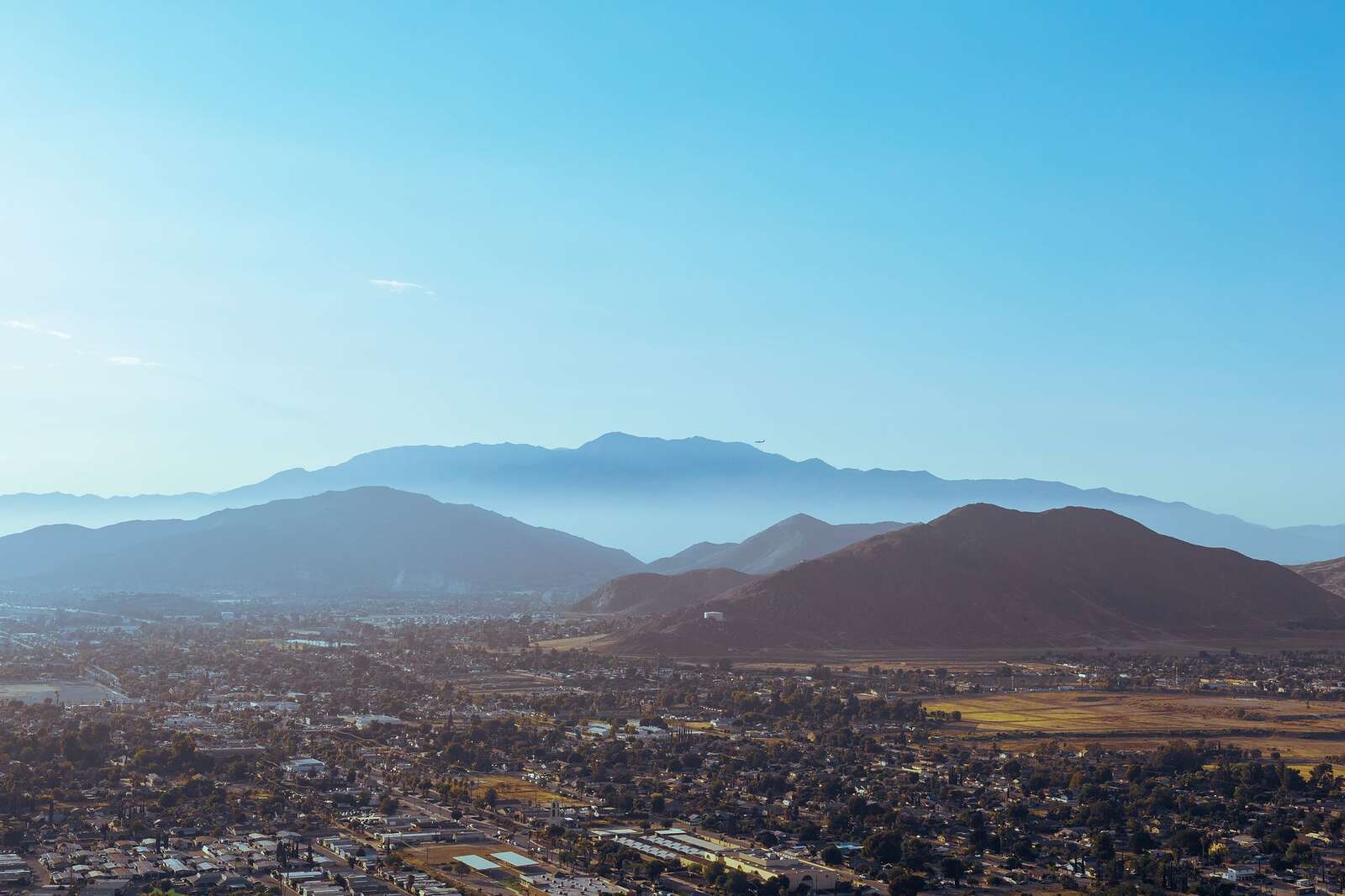 Aerial view of a valley city with mountains rising around it under a blue sky