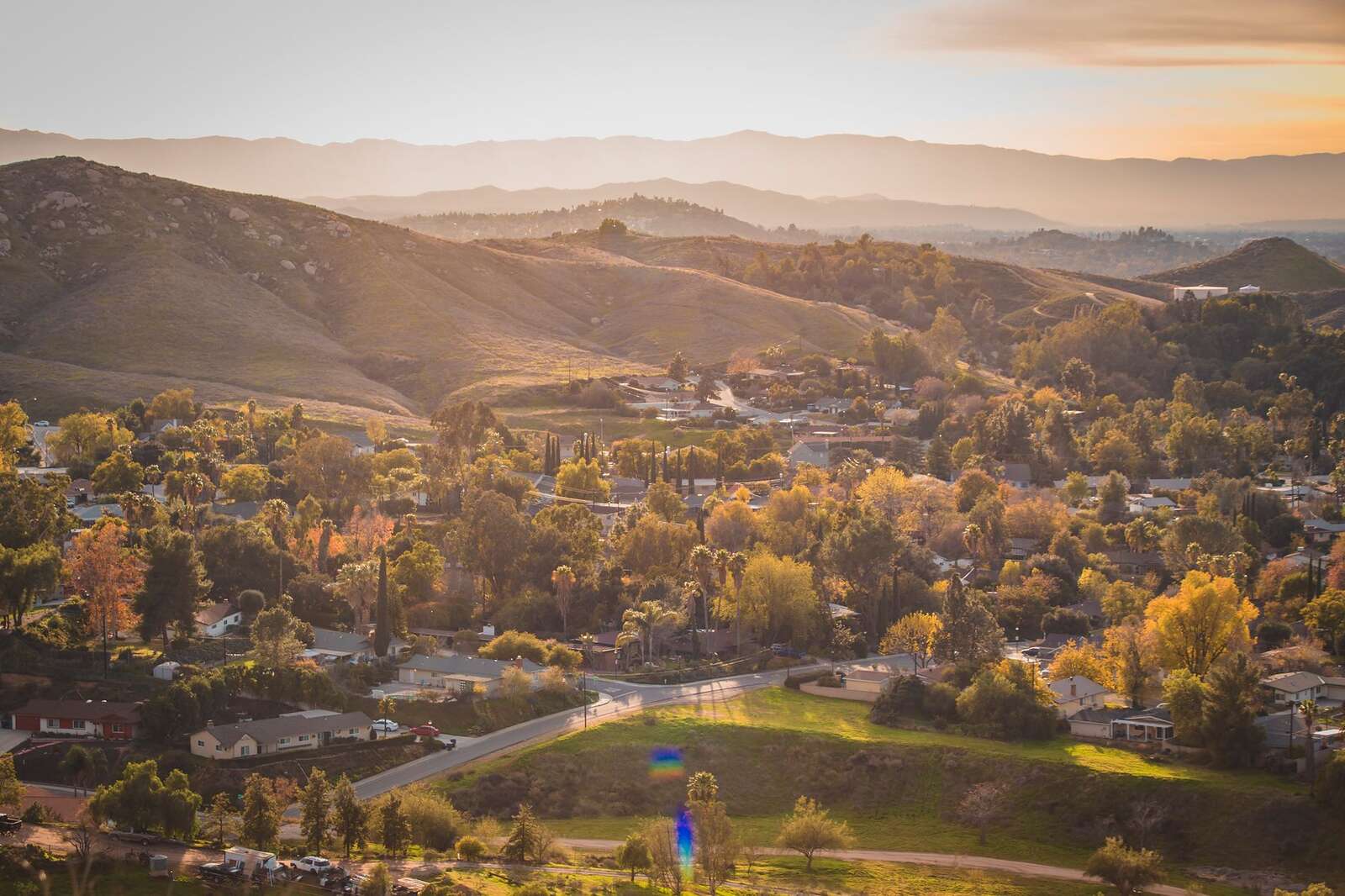 Aerial view of houses in a valley among rolling hills at sunset