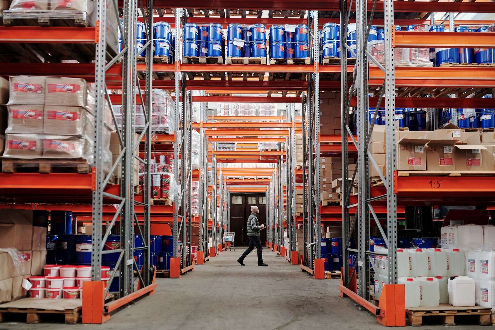 A long warehouse aisle between racks stacked with pallets of goods